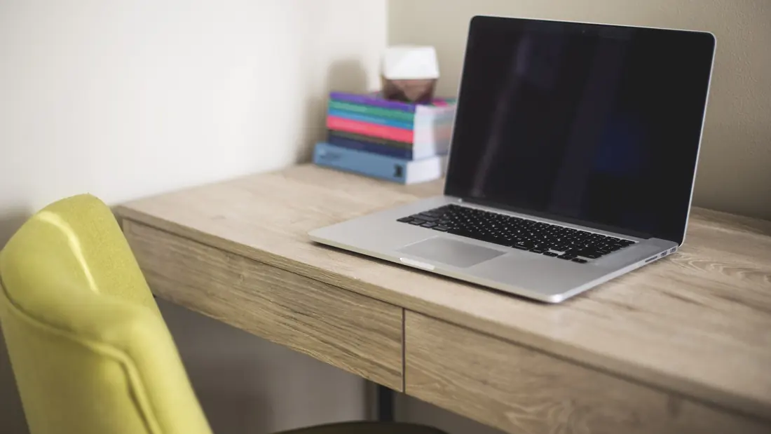 An open laptop and a stack of books on a desk