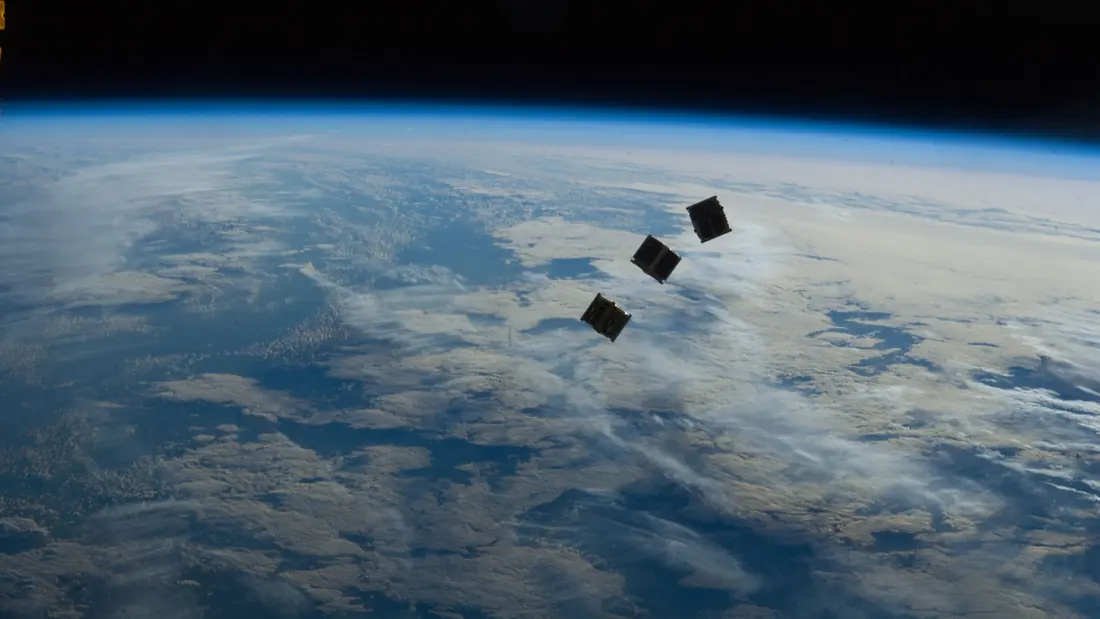 Astronauts deploying a cluster of tiny satellites outside the space station